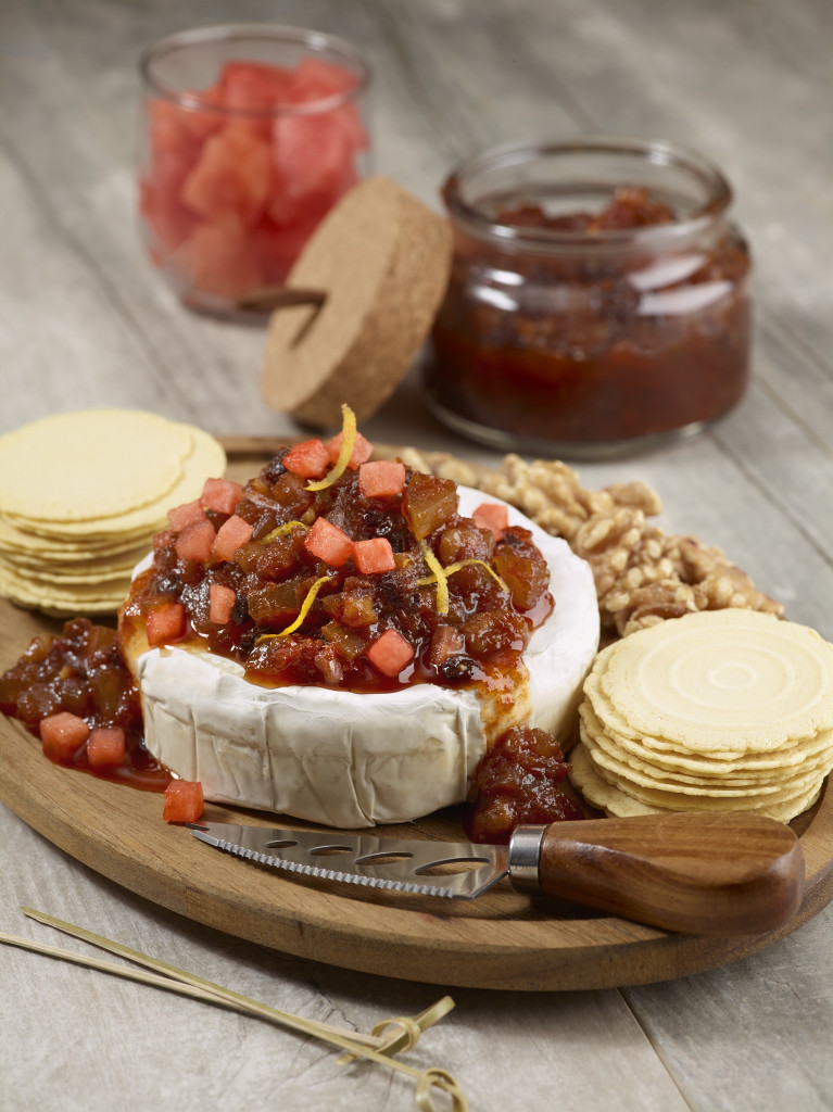 Chutney on top of brie with crackers on a serving board.