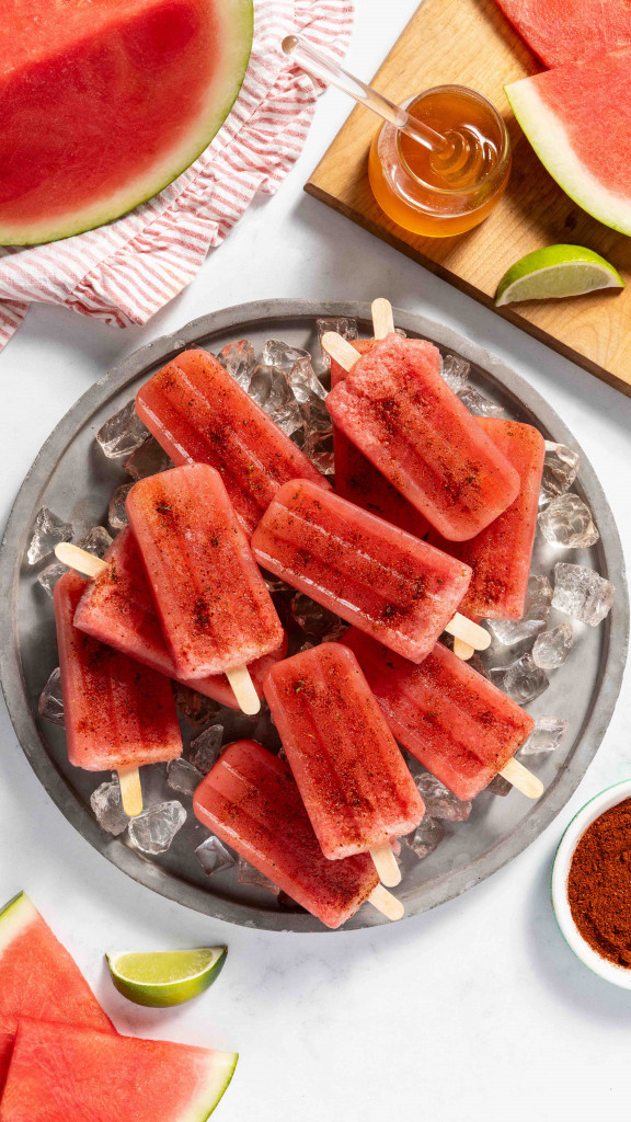 Popsicles on a bed of ice surrounded by fresh watermelon