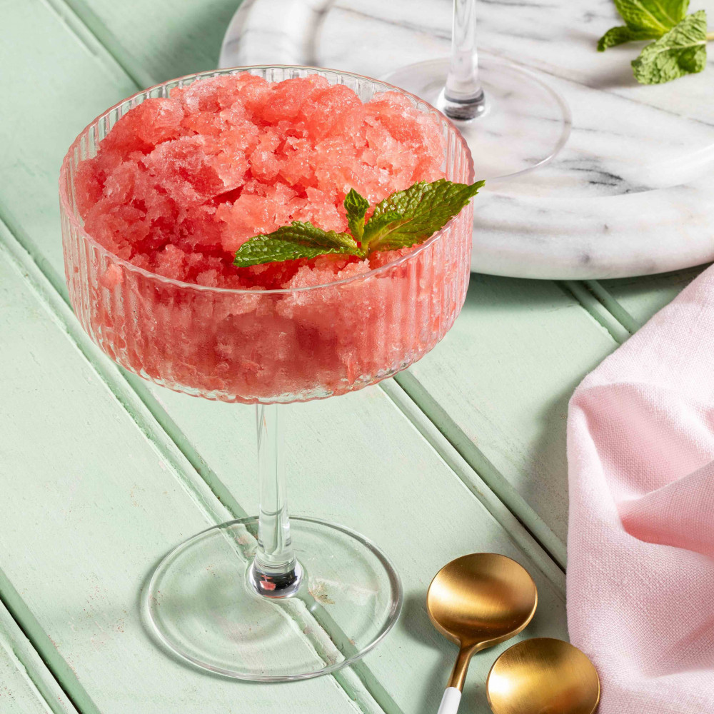Two glasses of watermelon mint granita with watermelon wedges in the background.