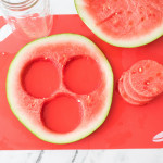 Round slice of watermelon on a cutting board with three round watermelon cut outs