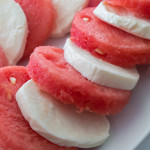 Watermelon and mozzarella cheese cut in rounds alternating on a white plate.