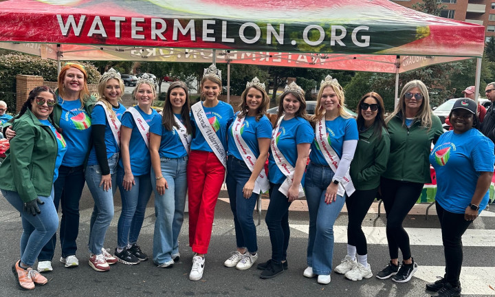 Group photo of watermelon queens and NWPB staff in front of Watermelon.org tent at the 2024 Marine Corps Marathon