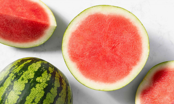 Seedless watermelon cut in half and quarters on a white table top